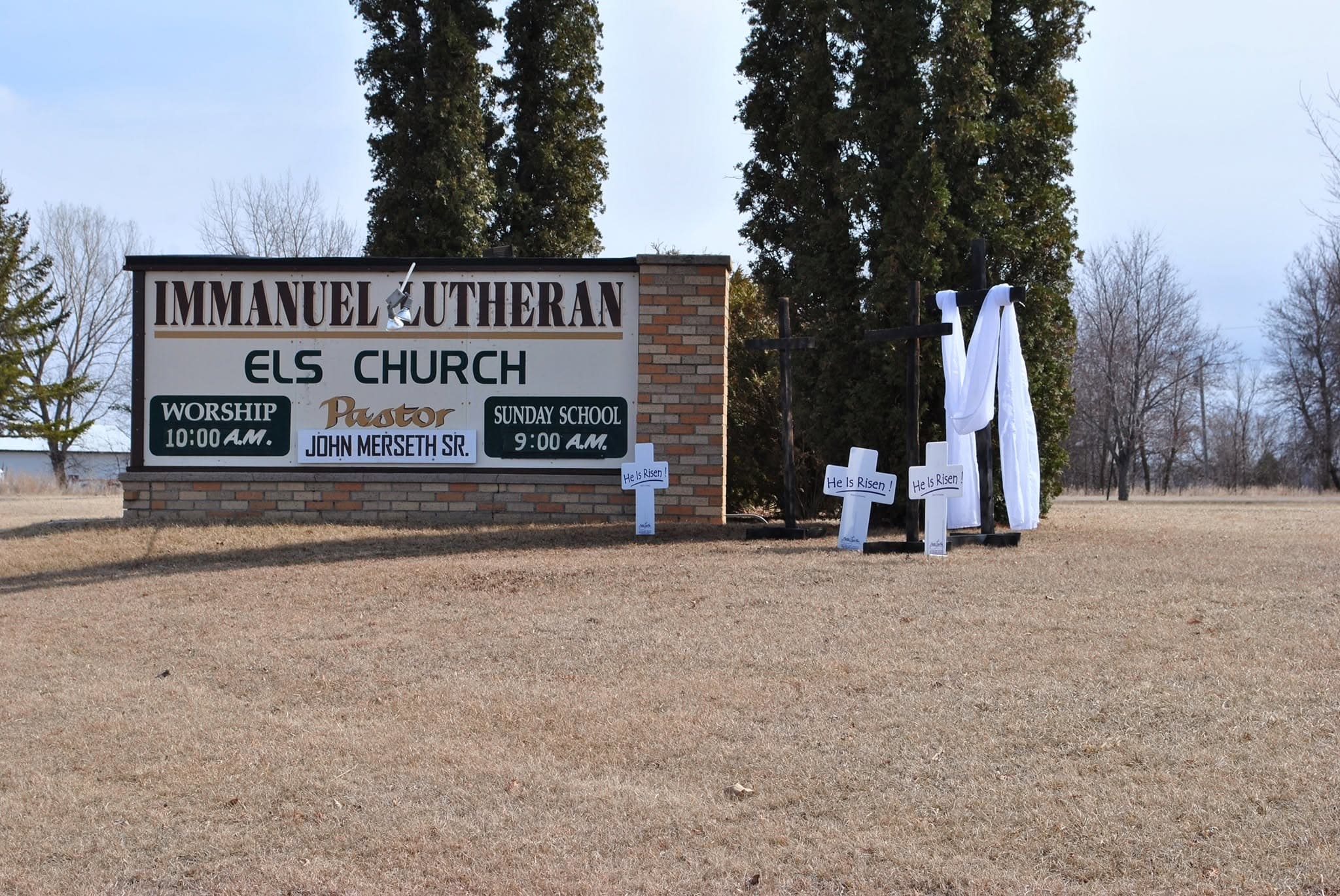 The roadside sign reading Immanuel Lutheran ELS Church, with three crosses draped in white beside it at Easter